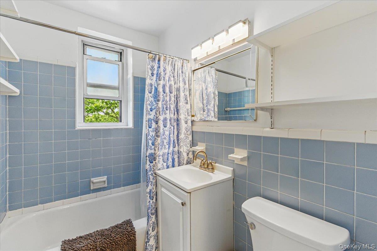 209-80 18th Avenue, Unit 4D Queens, NY 11360 - Photo 12 of 18 Bathroom featuring vanity, shower / tub combo, toilet, tile walls, and tasteful backsplash