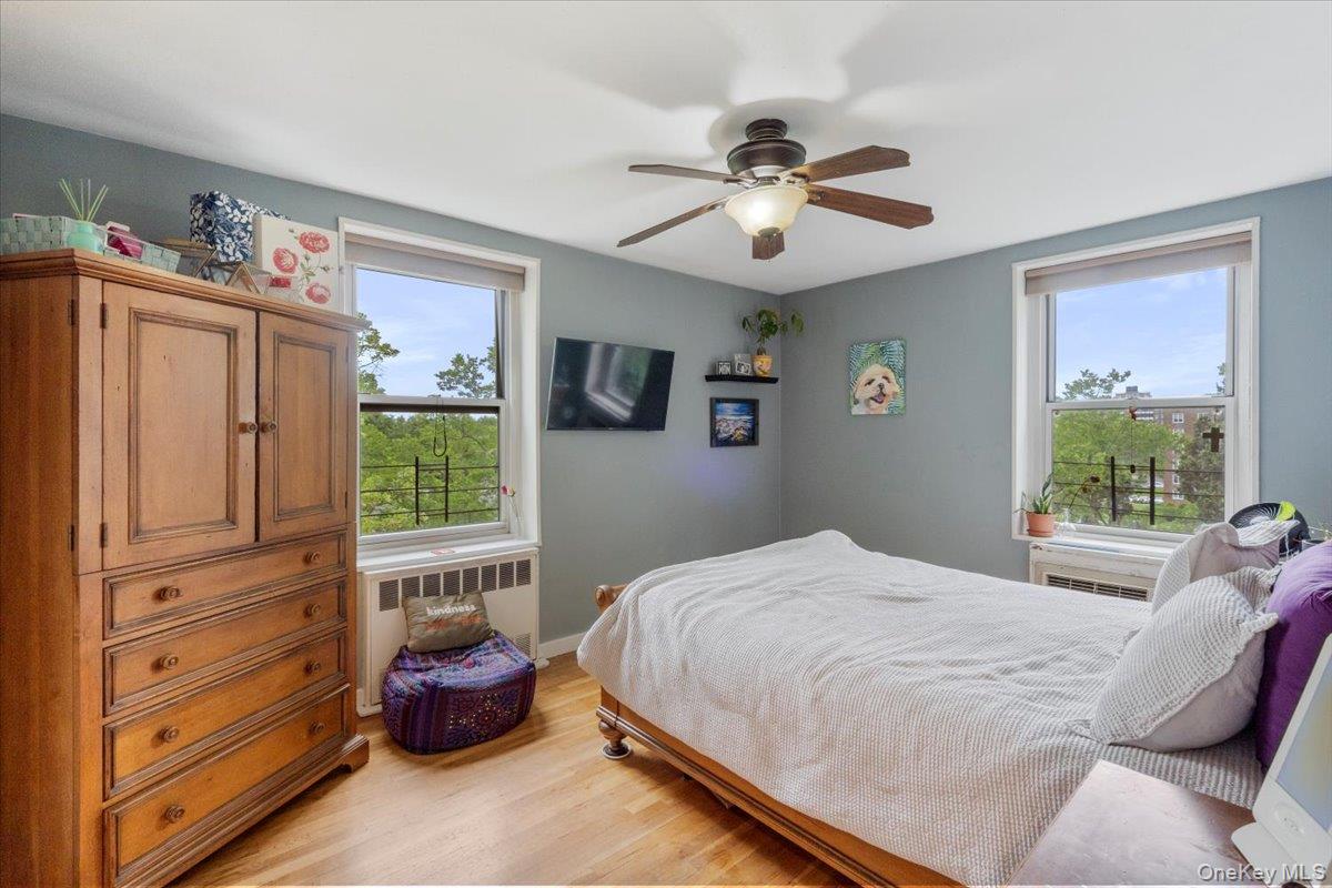 209-80 18th Avenue, Unit 4D Queens, NY 11360 - Photo 14 of 18 Bedroom with radiator heating unit, light wood finished floors, and a ceiling fan