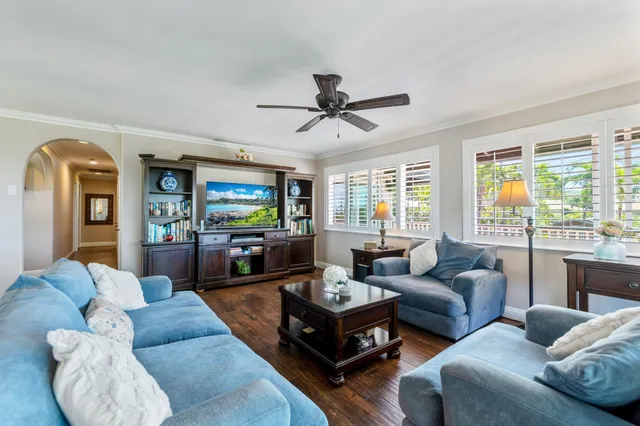 a living room with furniture ceiling fan and a large window
