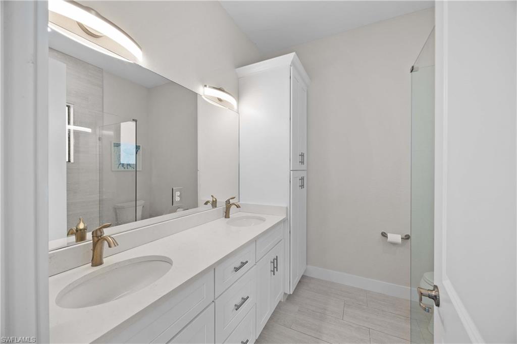 5832 Jasper Way, Unit 5102 Naples, FL 34114 - Photo 20 of 24 a bathroom with double vanity sinks and a mirror