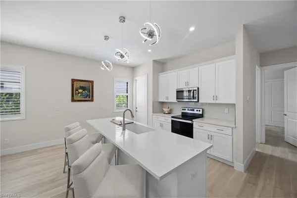 a kitchen with a refrigerator a stove a sink a dining table and chairs