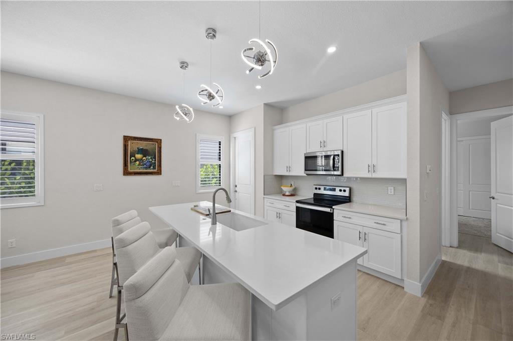 5832 Jasper Way, Unit 5102 Naples, FL 34114 - Photo 3 of 24 a kitchen with a refrigerator a stove a sink a dining table and chairs