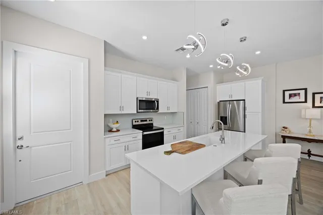 a kitchen with a refrigerator a stove top oven a sink a dining table and chairs