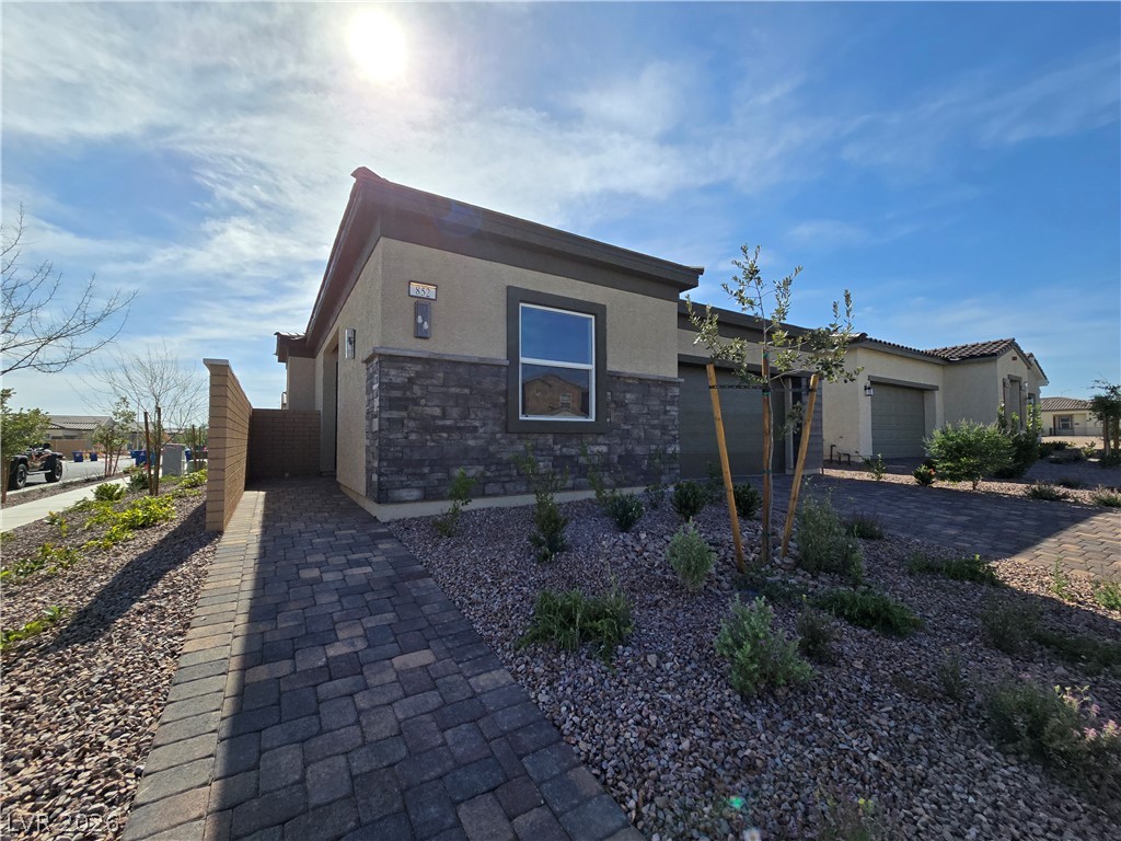 852 Weston Ridge Street Henderson, NV 89011 - Photo 3 of 28 A well-maintained paved walkway leads to a contemporary home with stone accents and an attached garage.