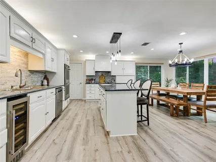 a kitchen with stainless steel appliances kitchen island granite countertop a stove a sink dishwasher a dining table and chairs with wooden floor