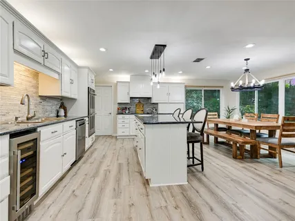 a kitchen with stainless steel appliances kitchen island granite countertop a stove a sink dishwasher a dining table and chairs with wooden floor