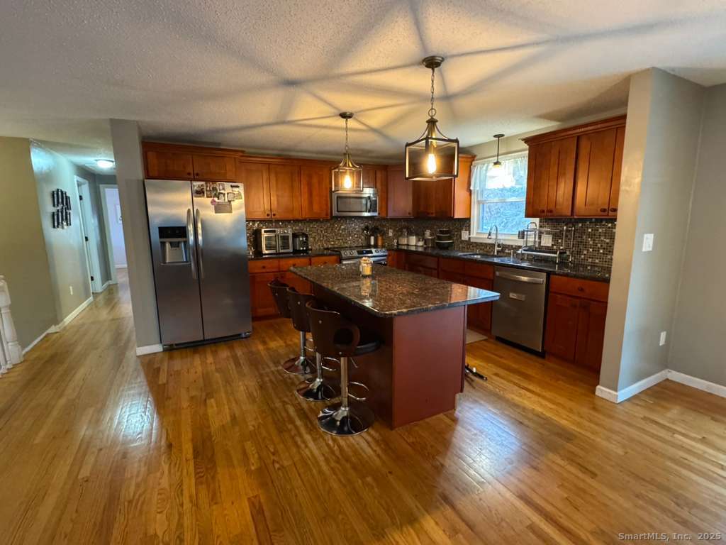 158 Swain Avenue Meriden, CT 06450 - Photo 3 of 25 a kitchen with stainless steel appliances granite countertop a sink a stove and a wooden floors