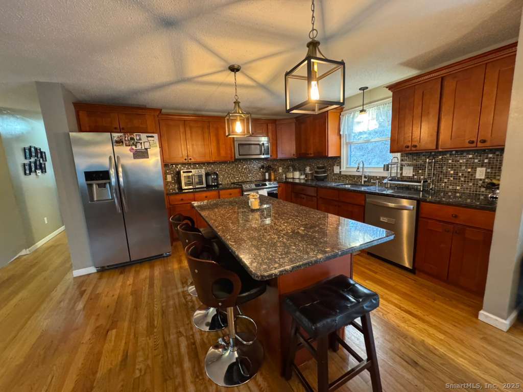 158 Swain Avenue Meriden, CT 06450 - Photo 4 of 25 a kitchen with stainless steel appliances granite countertop a sink a stove and wooden floor