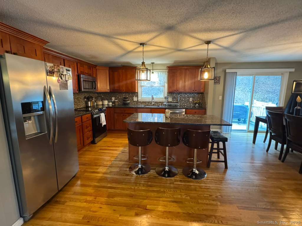 158 Swain Avenue Meriden, CT 06450 - Photo 5 of 25 a kitchen with stainless steel appliances granite countertop a refrigerator a stove a dining table and chairs with wooden floor