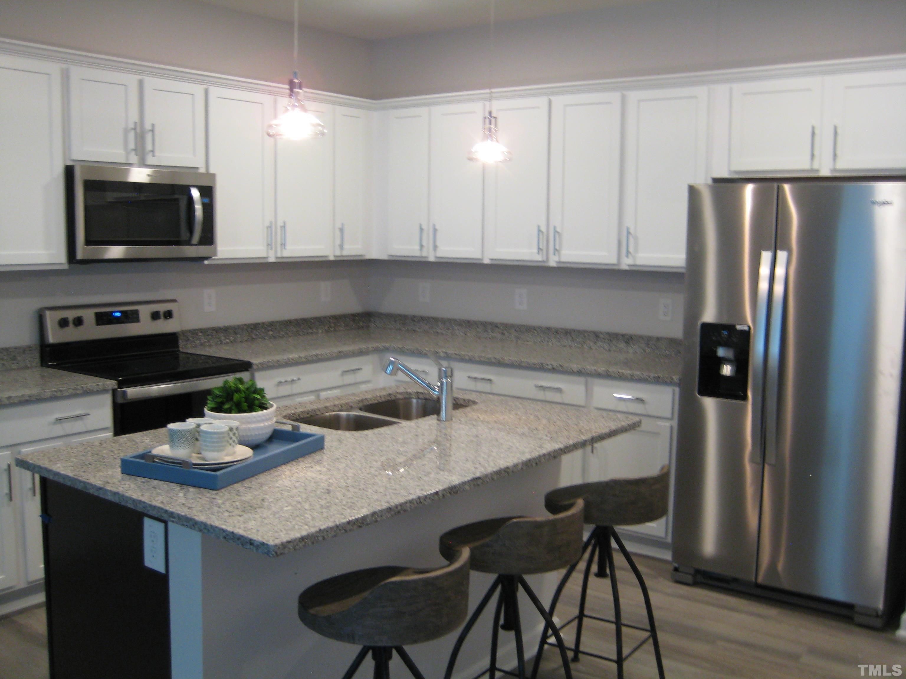 131 Rolesville Ridge Drive Rolesville, NC 27571 - Photo 2 of 8 a kitchen with stainless steel appliances a sink a microwave a refrigerator and white cabinets