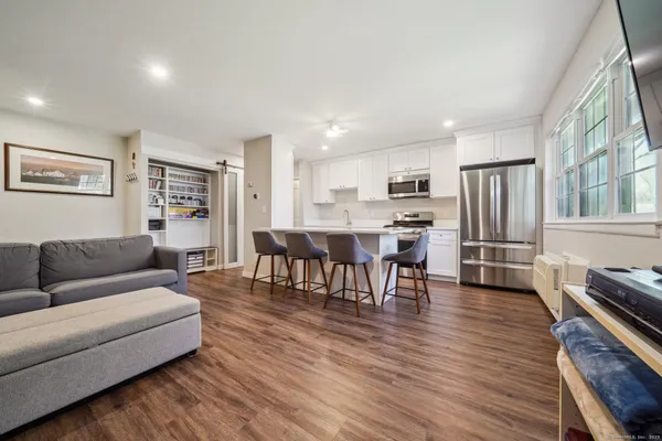 a living room with stainless steel appliances furniture and a wooden floor