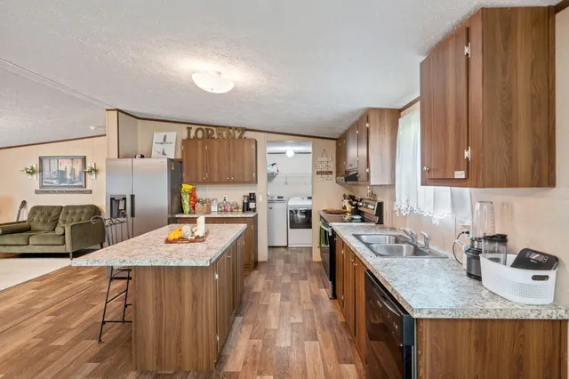 a kitchen with stainless steel appliances granite countertop wooden cabinets a stove top oven a sink dishwasher and a stove with wooden floor