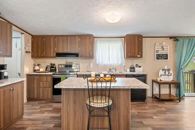 a kitchen with stainless steel appliances granite countertop a stove top oven a sink a dining table and chairs with wooden floor