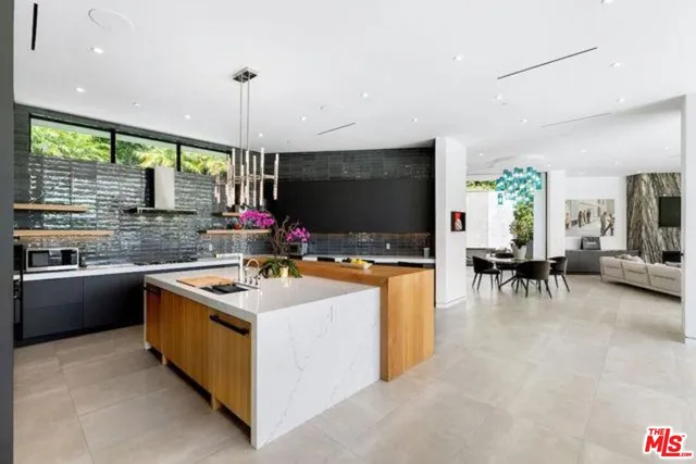 a kitchen with stainless steel appliances granite countertop a stove and a view of living room