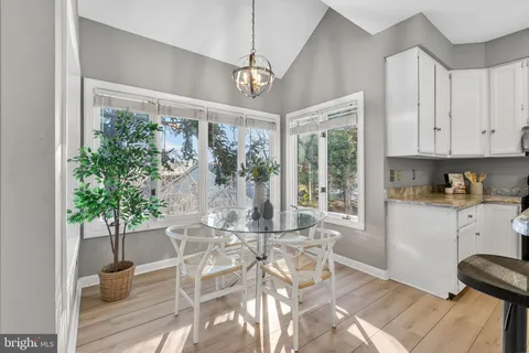 a dining room with wooden floor a chandelier a glass table and chairs