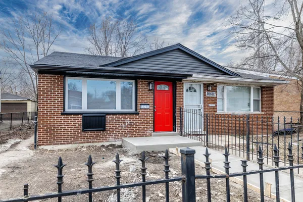 a front view of a house with large trees