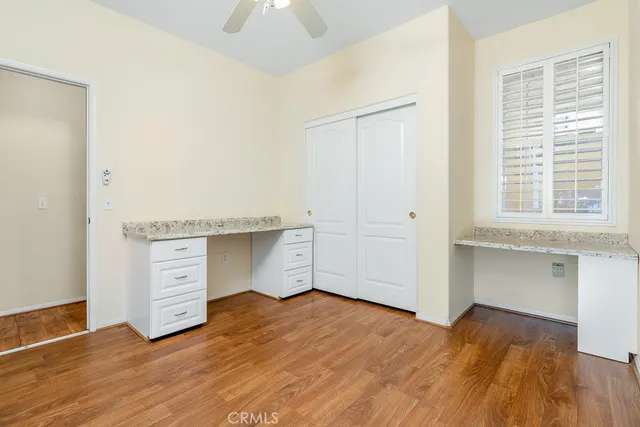 an empty room with wooden floor cabinet and windows