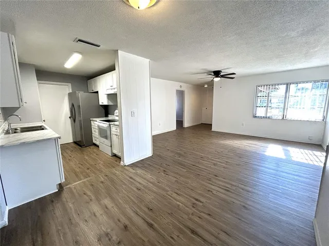 a view of a kitchen with wooden floor a sink a refrigerator and window