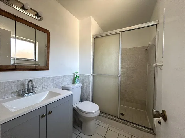 a bathroom with a toilet a sink a mirror a shower and vanity