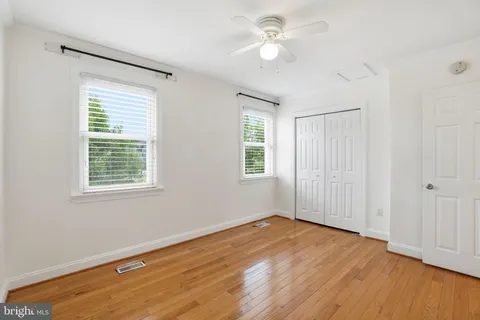 a view of empty room with wooden floor and fan