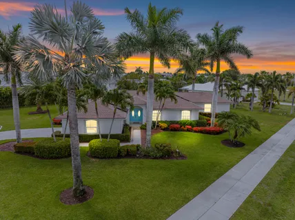 a front view of a house with a garden and trees