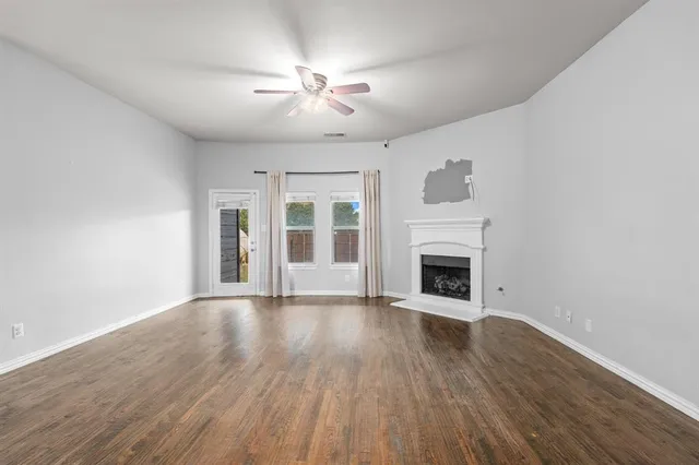 a view of an empty room with wooden floor fireplace and a window