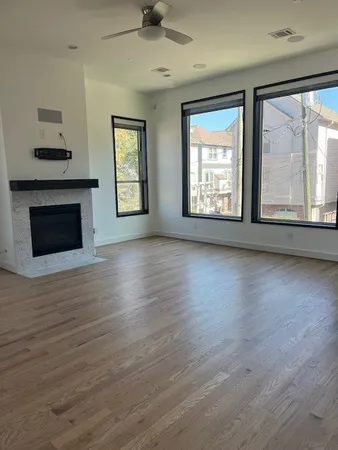 an empty room with wooden floor fireplace and windows