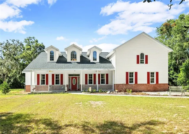 a front view of a house with swimming pool and large trees