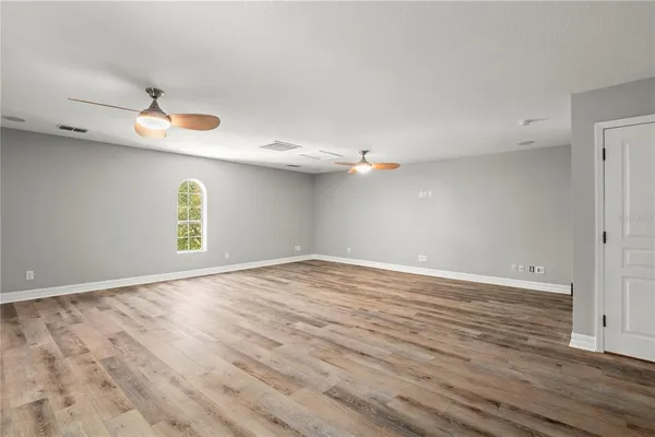a view of an empty room with window and wooden floor