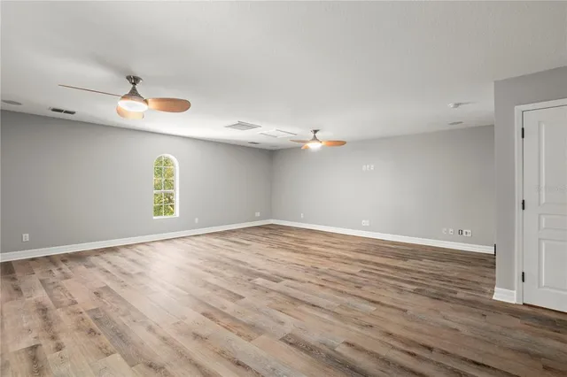 a view of an empty room with window and wooden floor