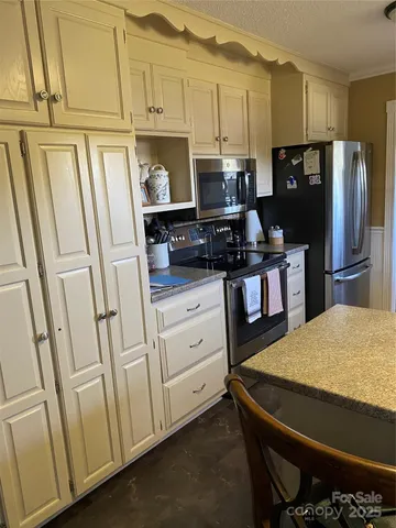 a utility room with stainless steel appliances a stove a sink a refrigerator and cabinets