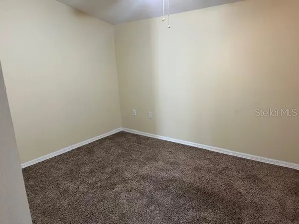 an empty room with a chandelier fan and windows