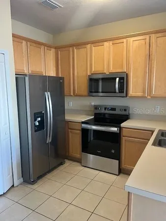 a kitchen with granite countertop a refrigerator and a stove top oven