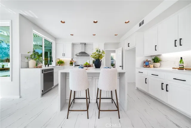 a kitchen with stainless steel appliances a stove a sink dishwasher and white cabinets with wooden floor