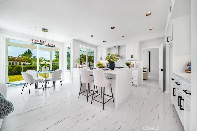 a kitchen with stainless steel appliances kitchen island granite countertop a table chairs and a refrigerator