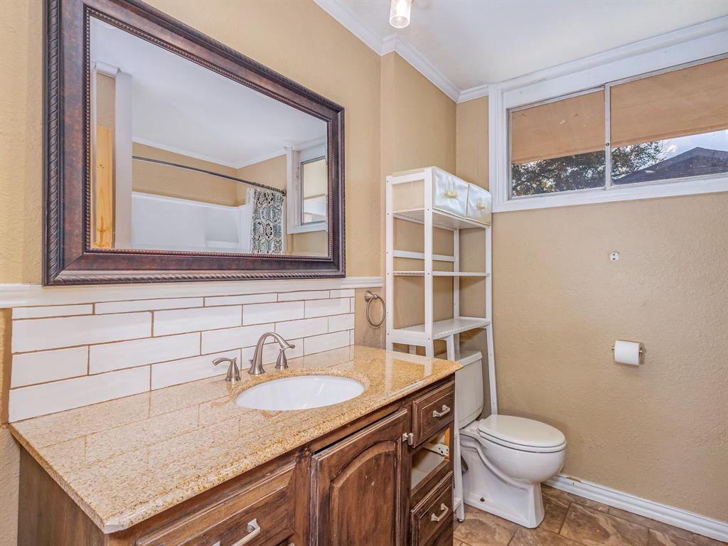 311 Miami Street Coleman, TX 76834 - Photo 14 of 31 a bathroom with a granite countertop sink toilet and mirror