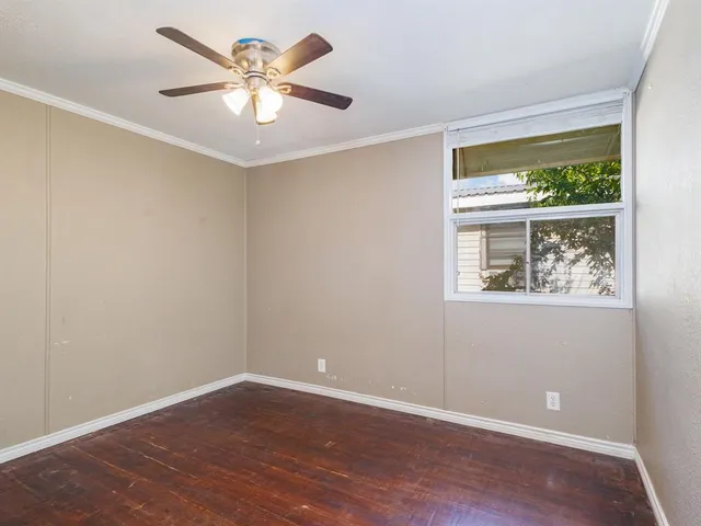 a view of an empty room with window and wooden floor