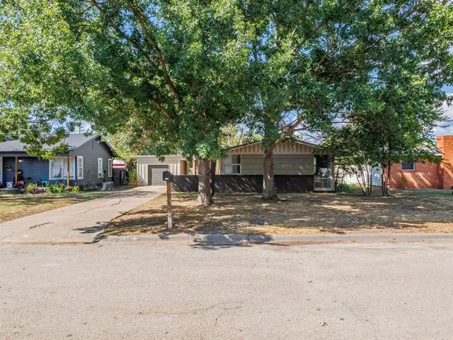 a view of a house with a yard and large tree