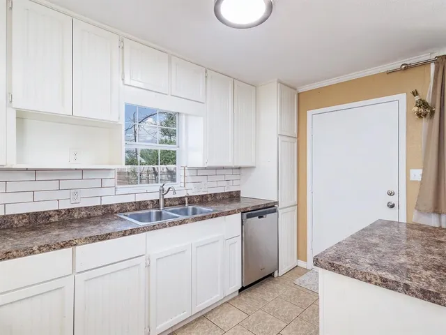 a kitchen with granite countertop a sink and a white cabinets
