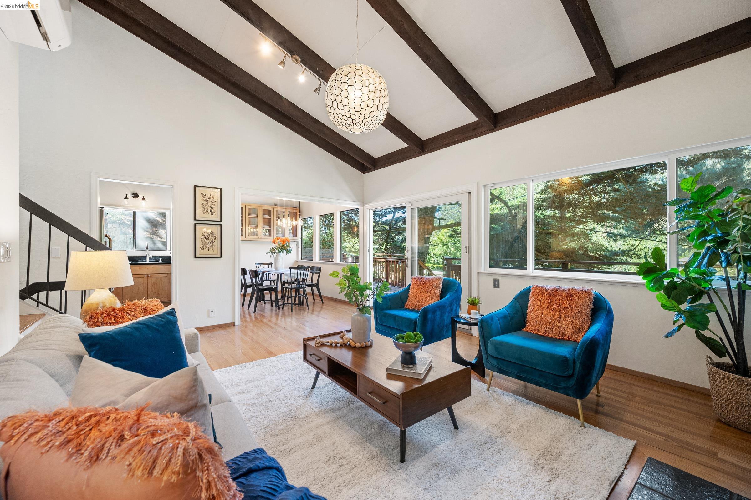 6600 Heather Ridge Way Oakland, CA 94611 - Photo 12 of 58 Living room featuring hanging lights, wood finished floors, and vaulted ceiling