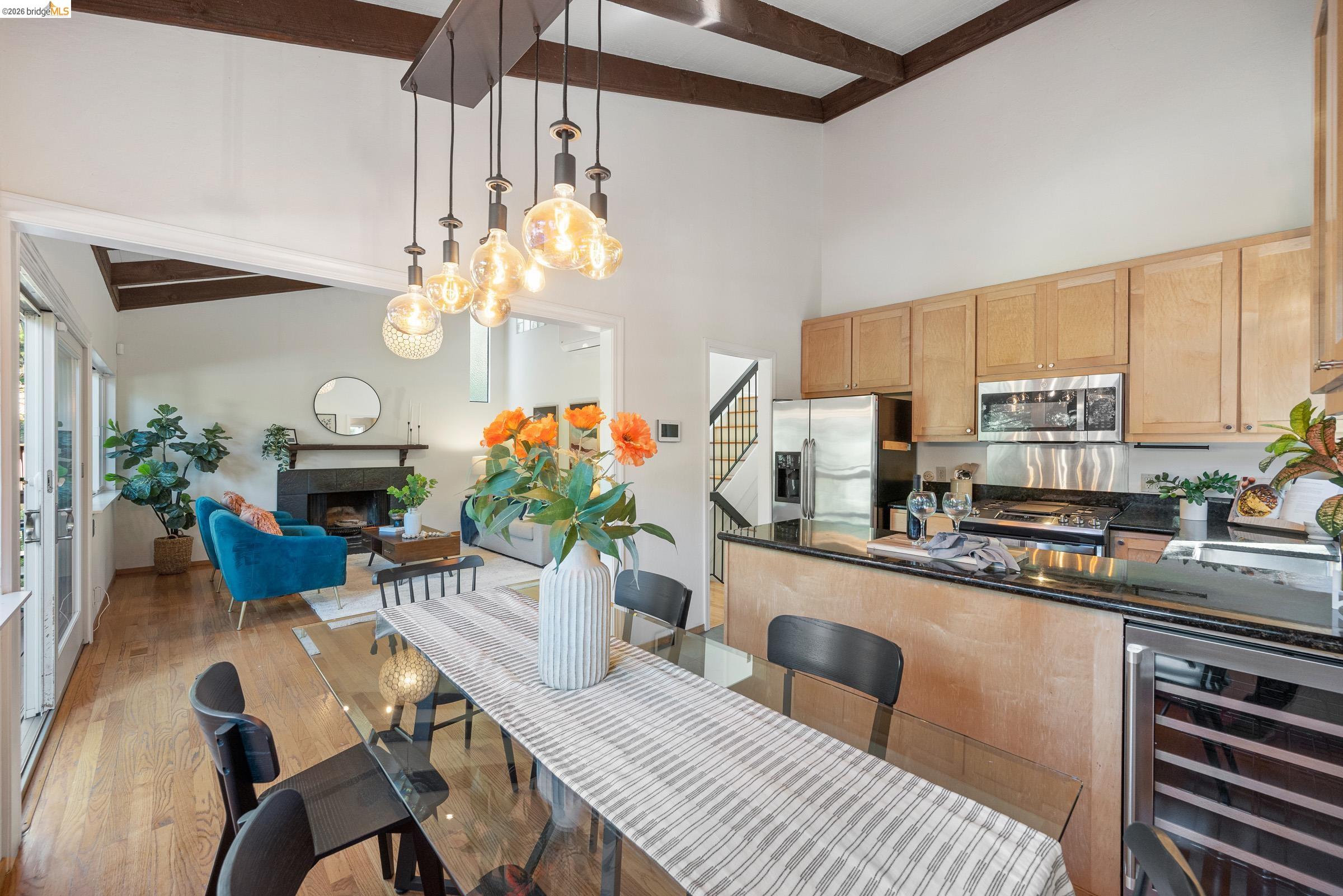 6600 Heather Ridge Way Oakland, CA 94611 - Photo 23 of 58 Kitchen featuring beverage cooler, dark stone countertops, a fireplace, decorative light fixtures, and stainless steel appliances