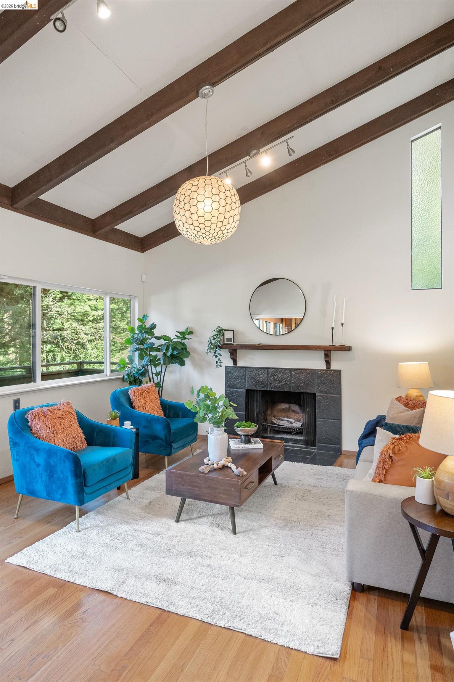 6600 Heather Ridge Way Oakland, CA 94611 - Photo 26 of 58 Living room featuring a tiled fireplace, light wood-style flooring, and lofted ceiling with beams