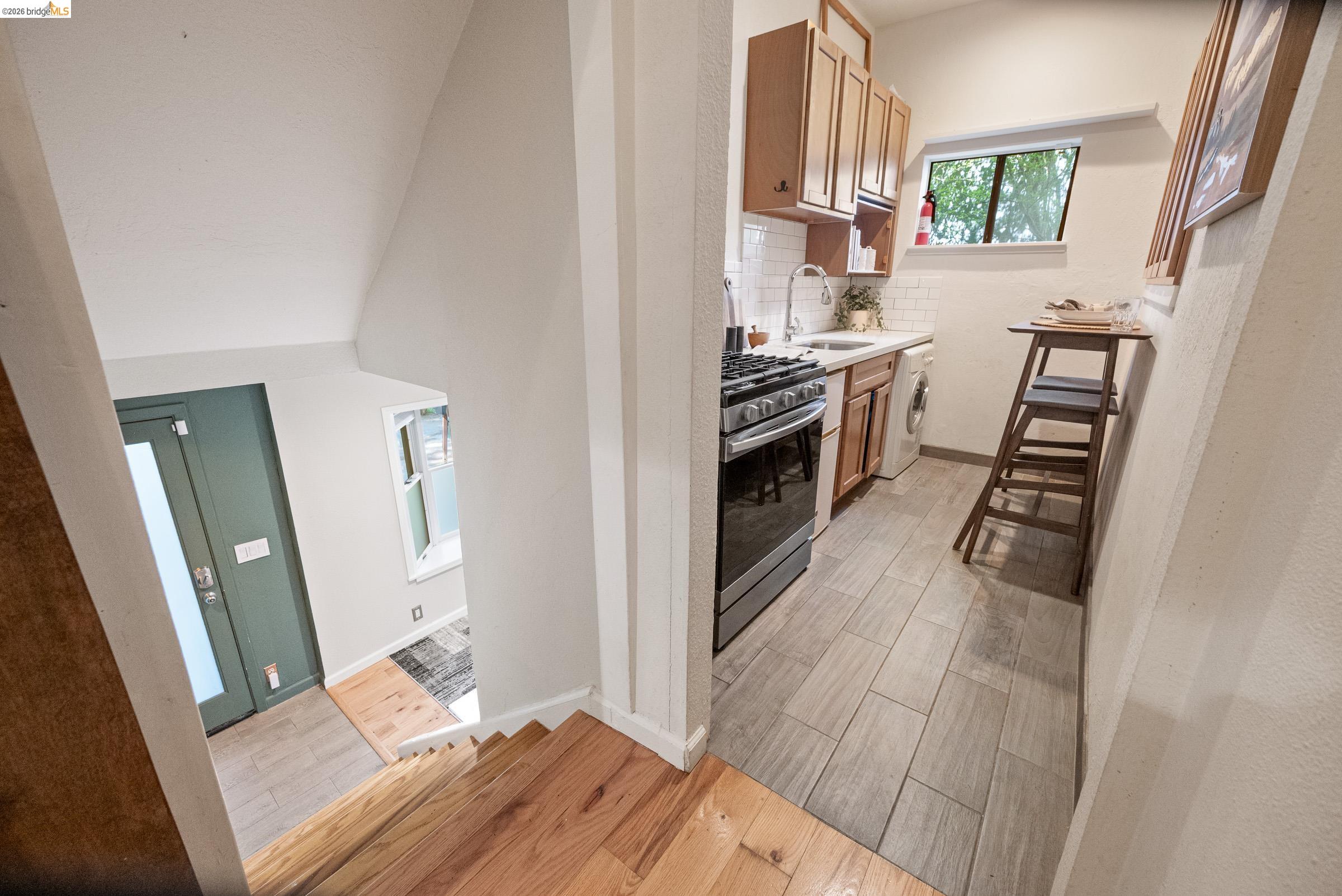 6600 Heather Ridge Way Oakland, CA 94611 - Photo 42 of 58 Kitchen featuring wood tiled floors, gas stove, light countertops, backsplash, and washer / clothes dryer