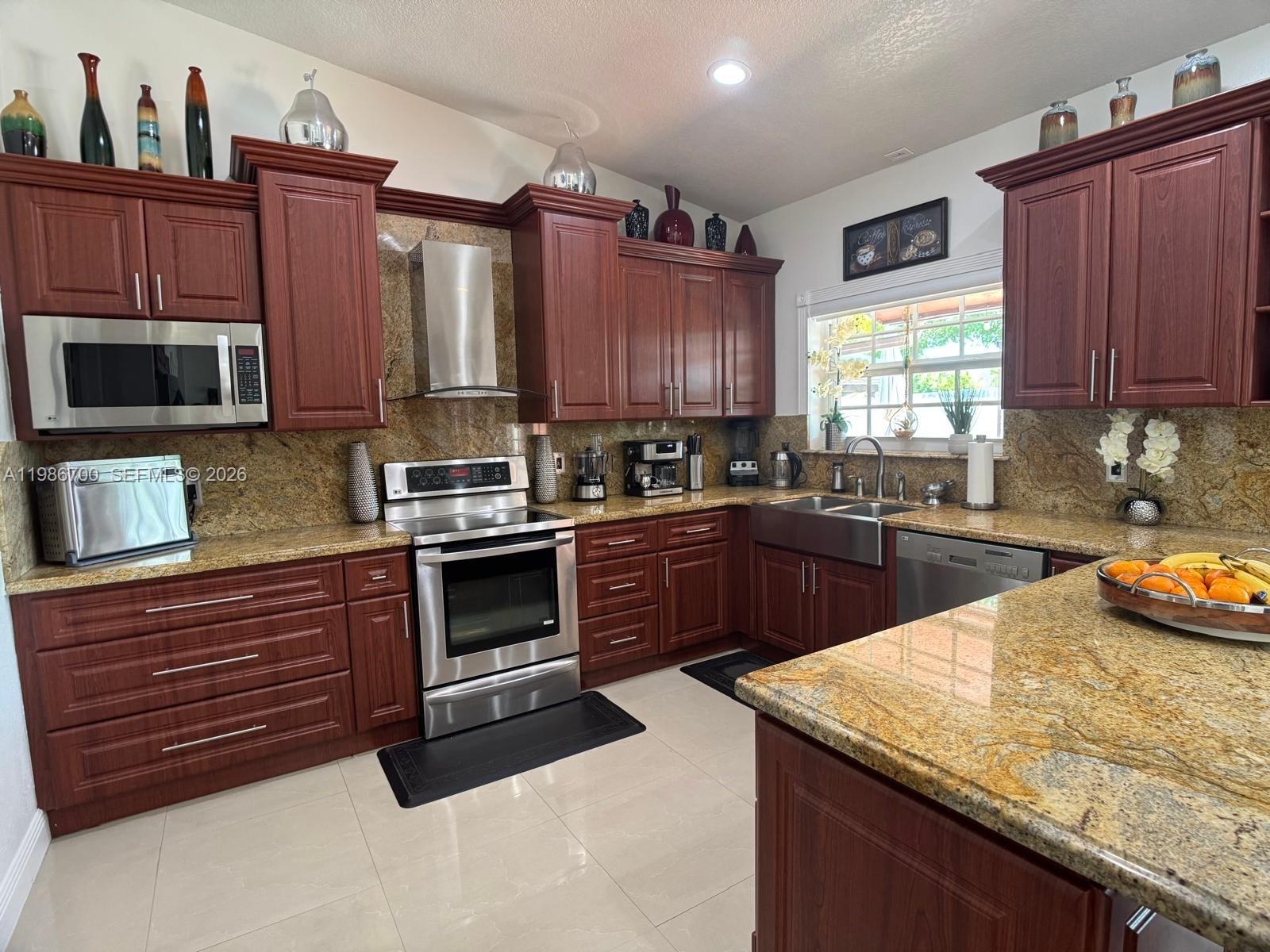 14620 Southwest 151st Terrace Miami, FL 33196 - Photo 9 of 30 a kitchen with granite countertop wooden cabinets and stainless steel appliances