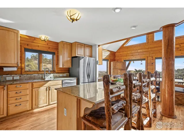 a kitchen with stainless steel appliances kitchen island granite countertop a table chairs and a refrigerator