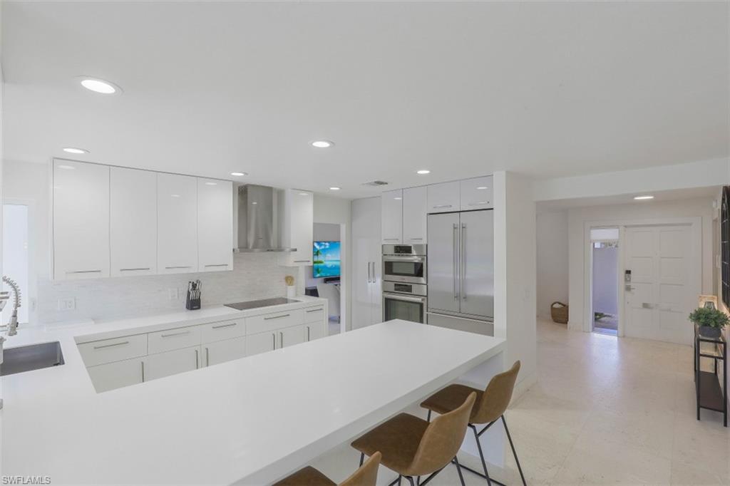 796 Ketch Drive Naples, FL 34103 - Photo 6 of 13 a kitchen with kitchen island a stove a table and chairs in it