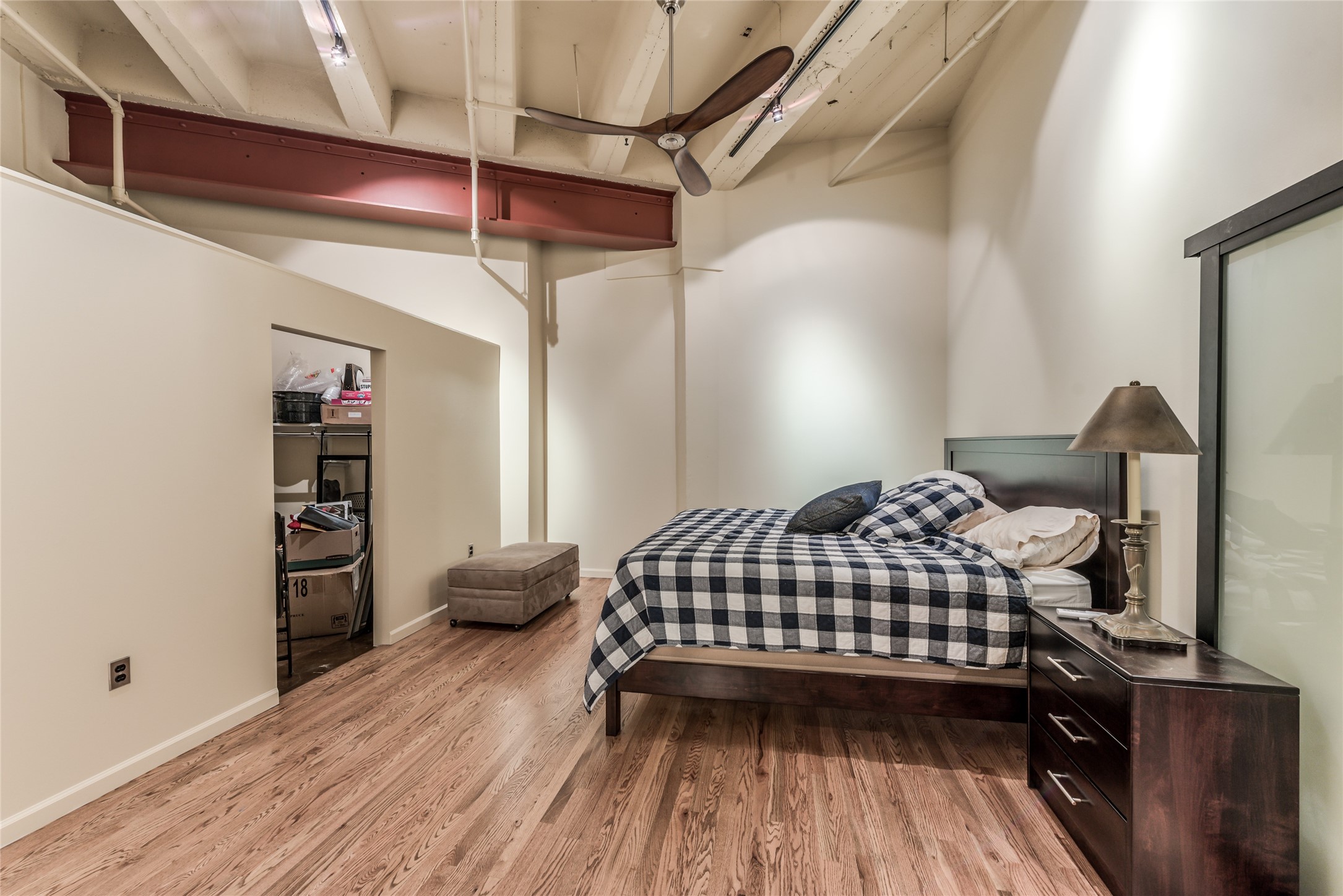 705 Main Street, Unit 215 Houston, TX 77002 - Photo 14 of 36 This photo features a bedroom with a modern industrial vibe, highlighted by exposed beams and a ceiling fan.