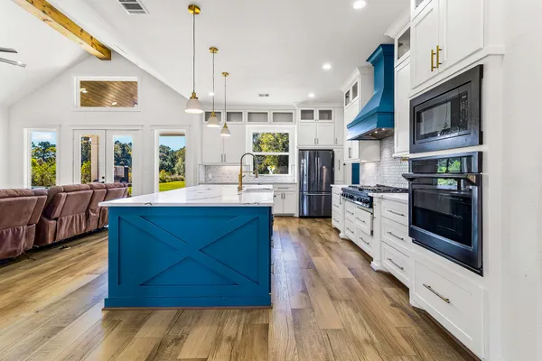 a large kitchen with stainless steel appliances wooden floor and a view of living room