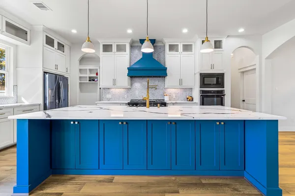 a kitchen with stainless steel appliances wooden cabinets a center island a stove and a cabinets