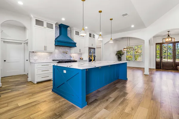 a kitchen with stainless steel appliances kitchen island granite countertop a stove a refrigerator a sink dishwasher and a wooden cabinets with wooden floor